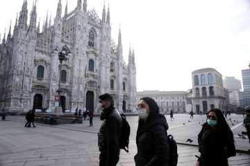 People wearing sanitary masks walk past the Duomo Gothic cathedral in Milan, Italy, on Sunday, Feb 23, 2020 (file photo)