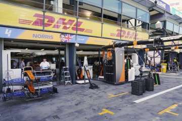 Technicians work around equipment and car parts in the The McLaren team pit at the Australian Formula One Grand Prix in Melbourne, Thursday, March 12, 2020. McLaren says it has withdrawn from the season-opening Australian Grand Prix in Melbourne after a team member tested positive for the coronavirus.