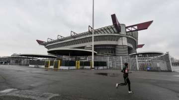 A woman jogs outside San Siro stadium where a Serie A soccer match between AC Milan and Genoa was supposed to take place but was instead postponed to May 13