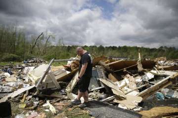 Aaron Pais kicks around debris at a mobile home park after a tornado hit on Monday, April 13, 2020, 