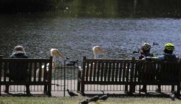  People sit on benches obeying the social distancing in St James's Park in London, as the country co