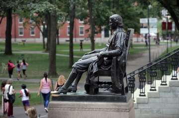 In this Aug. 13, 2019, file photo, students walk past the statue of John Harvard in Harvard Yard at 