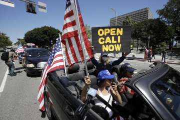 Protesters drive by in a convertible car during a rally calling for an end to California Gov. Gavin 