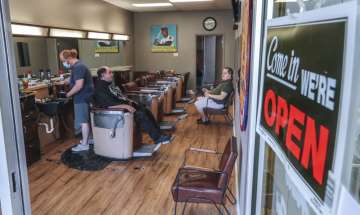 Barber and owner of Chris Edwards, left, wears a mask and cuts the hair of customer at Peachtree Bat