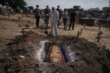 A cemetery worker stands before the coffin containing the remains of Edenir Rezende Bessa, who is su