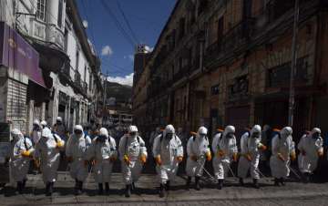 City workers fumigate a street to help contain the spread of the new coronavirus in La Paz, Bolivia, Thursday, April 2, 2020.