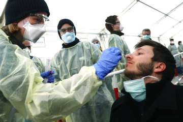 In this March 23, 2020, file photo, medical employees demonstrate testing, at a coronavirus test cen