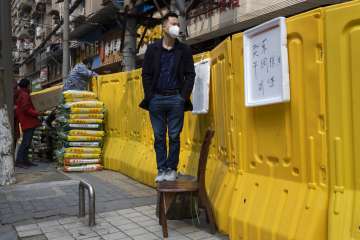A resident wearing a mask to protect against the spread of the coronavirus looks over barriers used 