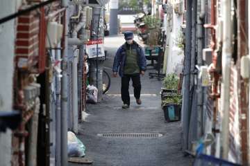 A man wearing a face mask to protect against the spread of the coronavirus, walks through an alley i