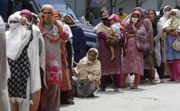 Women wait their turn to receive cash under the governmental Ehsaas Emergency Cash Programme for fam