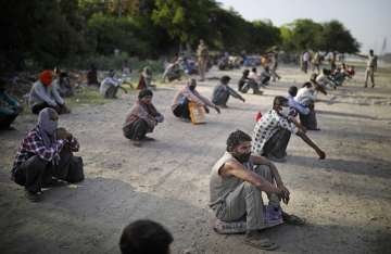 Indian migrant laborers and homeless people wait as they are evicted from the banks of Yamuna River 