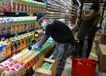 A clerk wears personal protective equipment as they stock shelves at a grocery store, Saturday, Apri