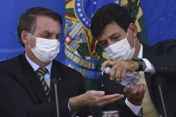 Brazil's Health Minister Luiz Henrique Mandetta, right, gives anti-bacterial gel to President Jair B