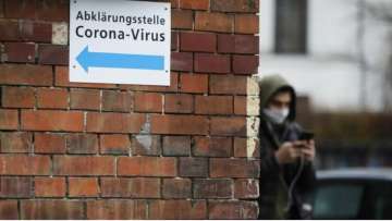 A man with a mask pass an information sign directing to a new set up test and information centre for the new coronavirus at the district Prenzlauer Berg in Berlin, Germany (file photo)