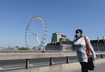 A woman wearing a protection mask to protect against coronavirus walks over Westminster Bridge in Lo