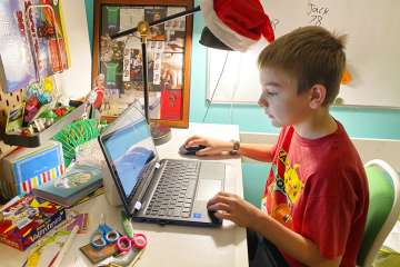 This April 9, 2020, photo released by Kara Illig shows her son, Eli Illig, 10, on his computer in Ebensburg, Pa. With schools closed around the world, kids are online more than ever before. Needless to say they are the easiest targets of hackers.?