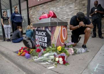 People gather and pray around a makeshift memorial, Tuesday, May 26, 2020, in Minneapolis, near the 