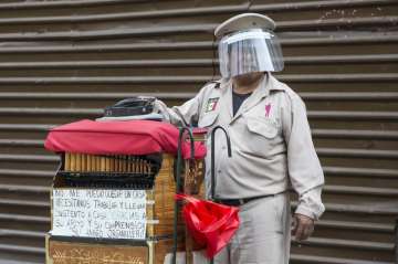 A barrel organ player wearing a face shield as a precaution against the spread of the new coronaviru
