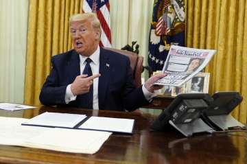 President Donald Trump holds up a copy of the New York Post as speaks before signing an executive or