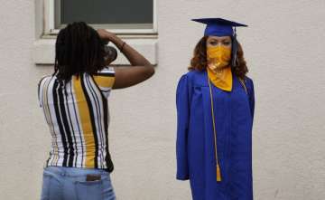 Anderson High School senior Teyaja Jones, right, poses in her cap and gown and a bandana face cover,