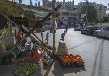 In this Tuesday, April 28, 2020 photo, a Palestinian vendor displays his vegetables in the street as