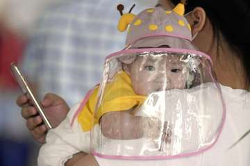 A baby with a face shield waits to board a plane at an airport in Wuhan, central China's Hubei Provi