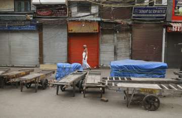 A daily wage migrant laborer walks across a closed wholesale market in the old quarters of Delhi dur