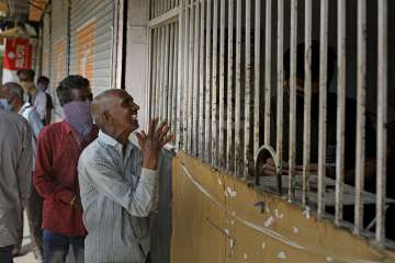 An Indian man reacts in joy after reaching the front of a long queue to buy liquor at one of the liq