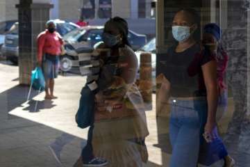 People wearing face masks to protect against coronavirus, walk past a closed pharmacy following undi