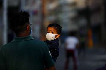 A Nepalese man carries his child as they return from a market during lockdown in Kathmandu, Nepal, S