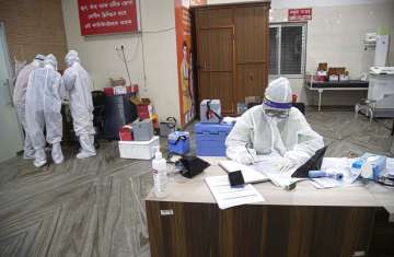 An Indian doctor wearing PPE kits writes thee details of a patient before collecting samples for swa