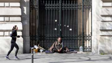 A woman runs as a homeless man looks on during the lockdown of coronavirus in Paris on March 27, 2020 (representational image)