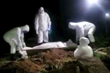 In this May 2020 frame grab from video provided by a Yemeni activist, men in protective gear bury a 