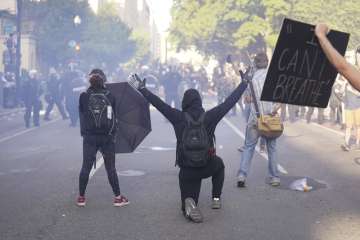 Demonstrators kneel in front of a line of police officers during a protest for the death of George F