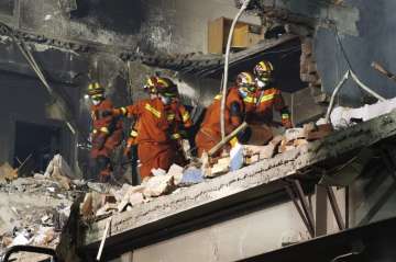 Firefighters look for victims in damaged buildings in the aftermath of a tanker truck explosion near