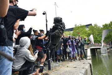 Protesters throw a statue of slave trader Edward Colston into the Bristol harbour, during a Black Lives Matter protest rally, in Bristol, England, Sunday June 7, 2020, in response to the recent killing of George Floyd by police officers in Minneapolis, USA, that has led to protests in many countries and across the US. (Ben Birchall/PA via AP)
