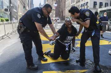 New York Police Department officers attempt to detain a protester who defaced with black paint the B