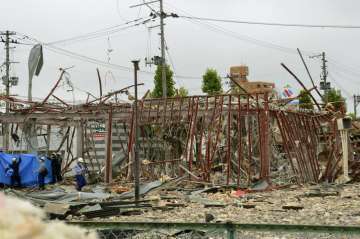 Investigators work near a damaged building following an explosion in Koriyama, Fukushima prefecture,