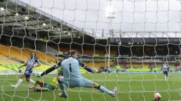 Brighton's Leandro Trossard, left, scores his side's opening goal past Norwich City's goalkeeper Tim Krul during the English Premier League soccer match between Norwich City and Brighton & Hove Albion at Carrow Road Stadium in Norwich, England, Saturday, July 4