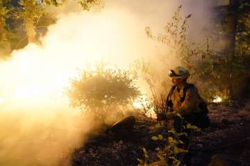 Firefighter Jeremy Damon of the Nevada Yuba Placer Fire Dept. monitors a controlled burn in the back