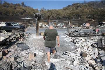 Artist Marcia Ritz, 77, leaves after looking through the rubble of her manufactured home at the Span