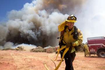 A firefighter battles a brush fire at the Apple Fire in Cherry Valley, Calif., Saturday, Aug. 1, 202