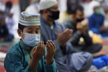 A young Muslim wears a face mask to protect against coronavirus as Muslims gather to pray at Minhaj-