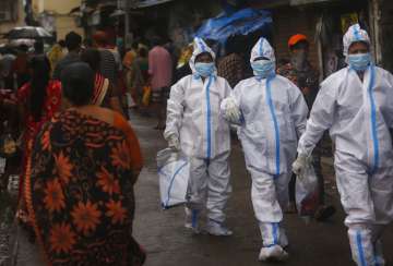 Health workers return after screening people for COVID-19 symptoms in Dharavi, one of Asia's biggest