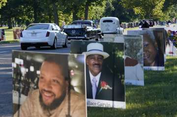 A procession of vehicles drive past photos of Detroit victims of COVID-19, Monday, Aug. 31, 2020 on 