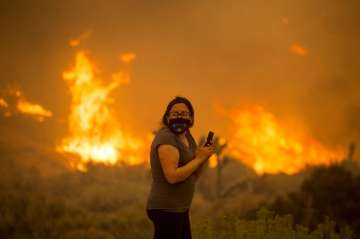 A woman watches as the Bobcat Fire burns in Juniper Hill, Calif., Friday, Sept. 18, 2020. (AP Photo/