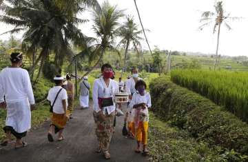 People wearing face masks as a precaution against coronavirus outbreak walk to a temple at a village