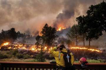 In this Aug. 21, 2020, file photo, a firefighter rubs his head while watching the LNU Lightning Complex fires spread through the Berryessa Estates neighborhood of unincorporated Napa County, Calif. Deadly wildfires in California have burned more than 4 million acres (6,250 square miles) this year — more than double the previous record for the most land burned in a single year in the state. California fire officials said the state hit the astonishing milestone Sunday, Oct. 4, 2020 with about two months remaining in the fire season. (AP Photo/Noah Berger, File)