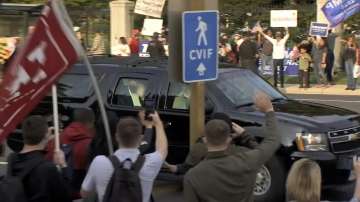 In this image from video, President Donald Trump waves as he drives past supporters gathered outside