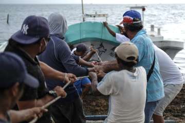 Fishermen pull in a boat before the arrival of Hurricane Delta in Puerto Juarez, Cancun, Mexico, Tue